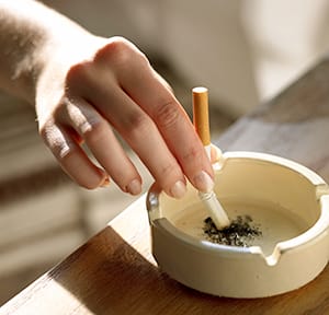 Woman's hand putting out a cigarette in an ash tray.